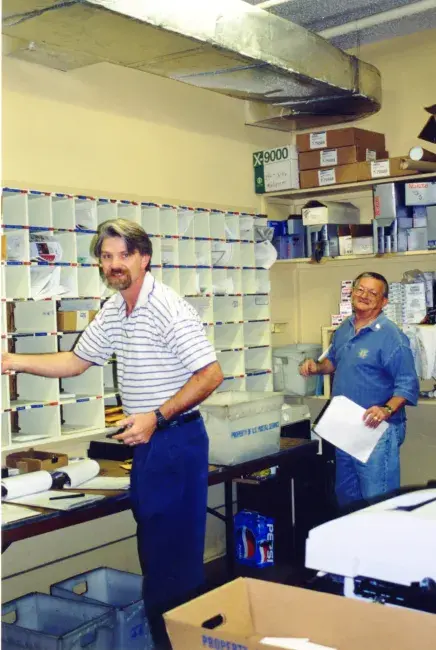 Bennett in old mailroom, sorting letters into boxes