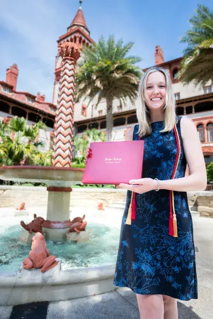 Ann Beverly standing with a degree next to the fountain in the Ponce courtyard