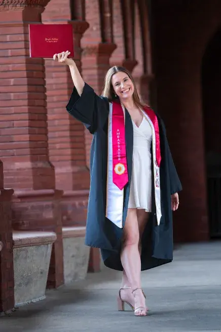 Kailey Tucker posing while holding her degree above their head