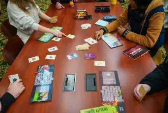 Aerial view of students playing board game at Library table