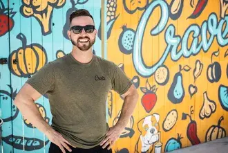 Alumni-Owned Businesses.jpg Flagler alum and business owner stands in front of sign for Crave food truck.