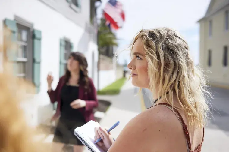 A Flagler College student takes notes during an outdoors lecture in the historic area of the city.