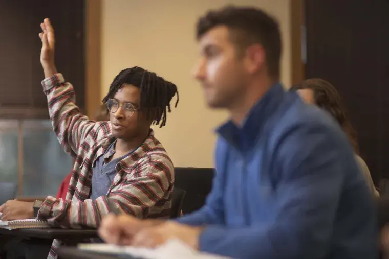 A Flagler College student raises his hand in class.