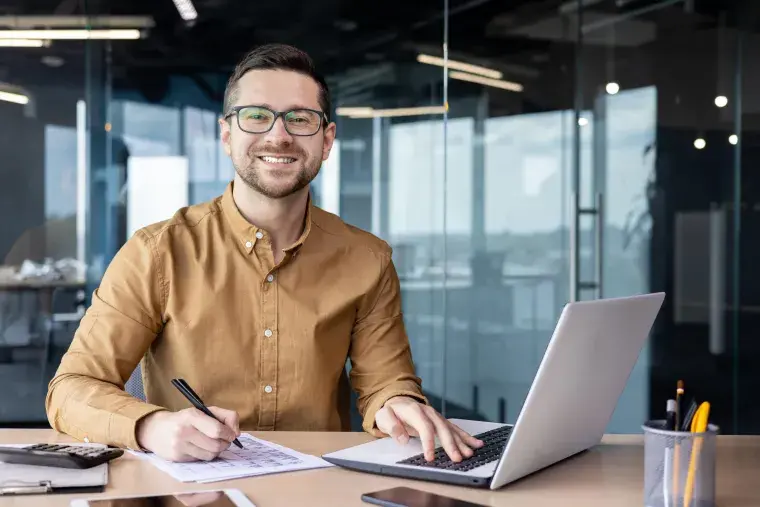 A student with a laptop smiles.