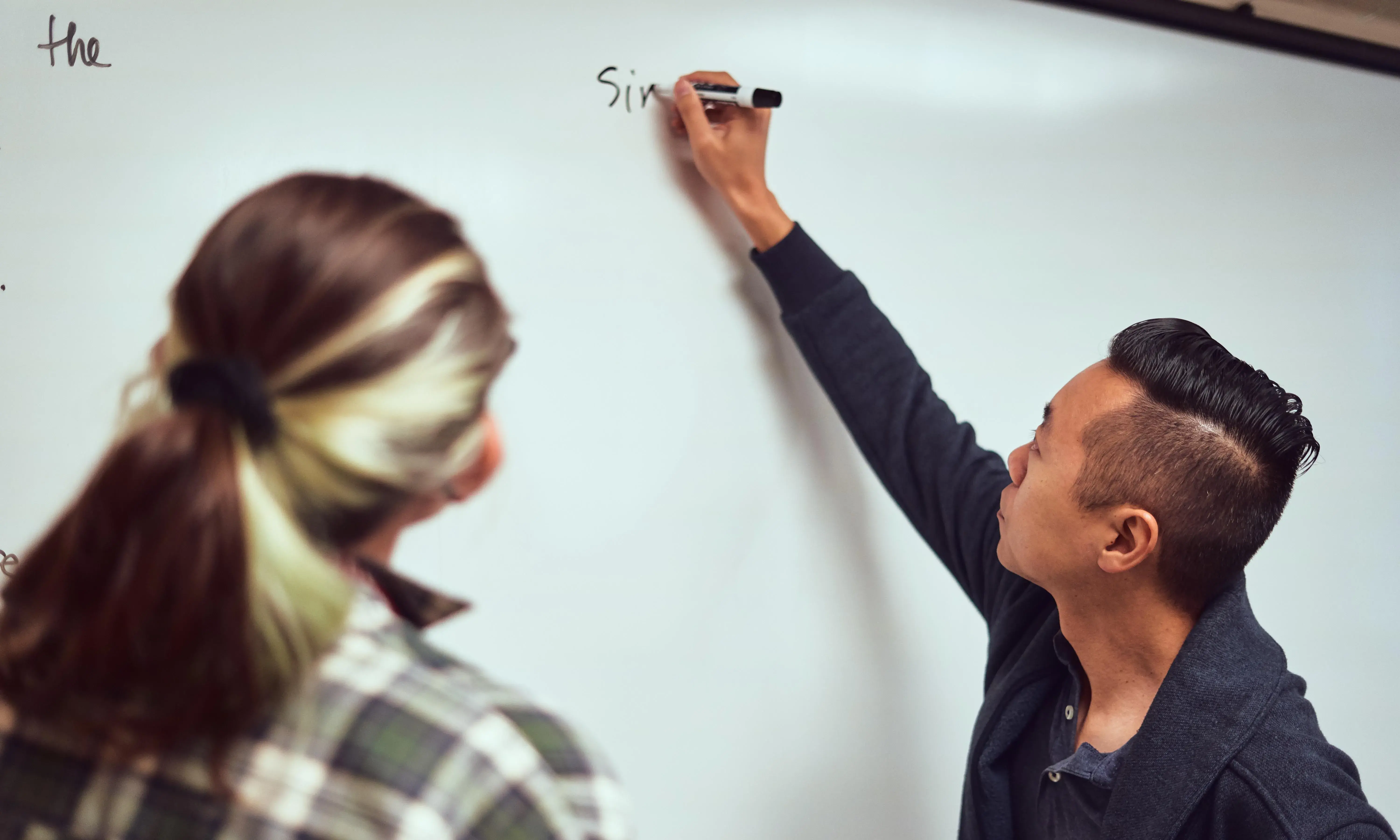 A Flagler College faculty member writes on a whiteboard.