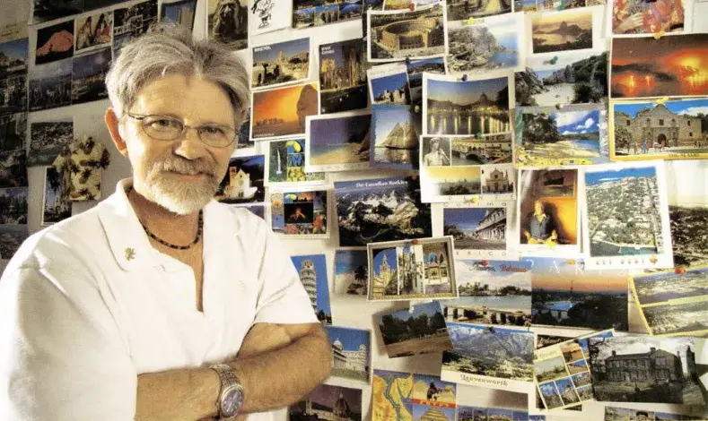 FC Magazine photo of Bennett standing in front of his original postcard wall