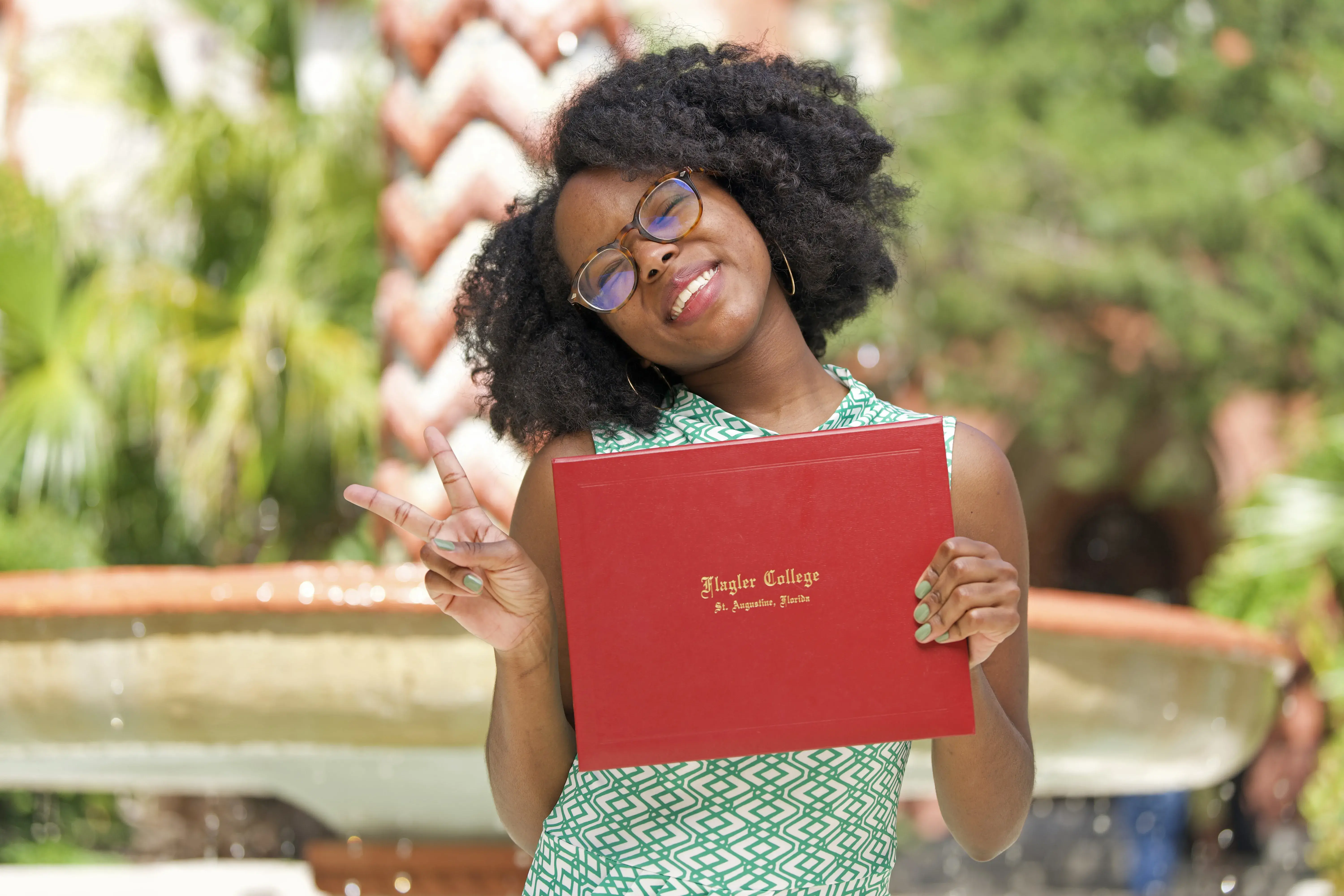 Chatmon smiling with diploma in front of fountain